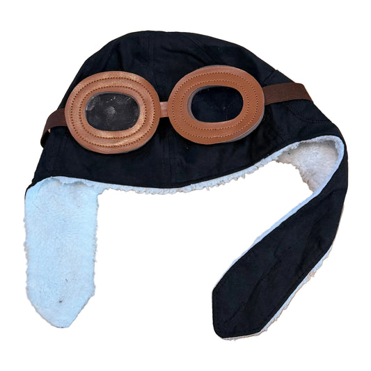 Black winter hat with brown goggles on a wooden surface